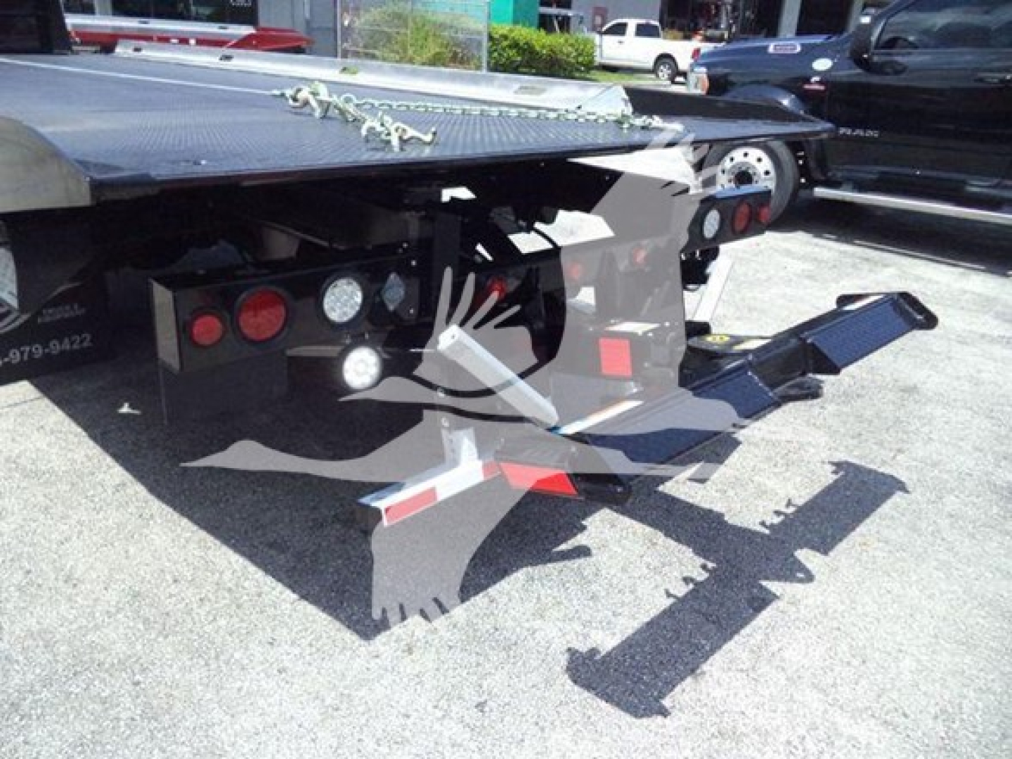 Truck bed of a Freightliner M2 106 Plus rollback with tow hitch and hydraulic system.