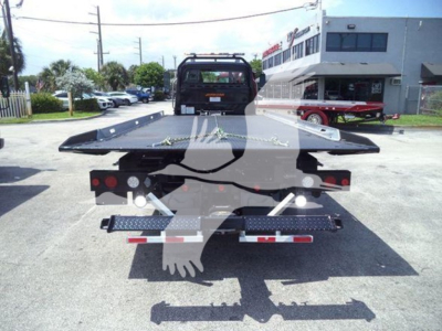 Flatbed tow truck rear view showing heavy-duty platform and winch with LED taillights, trailer hitch, and bumper guards.