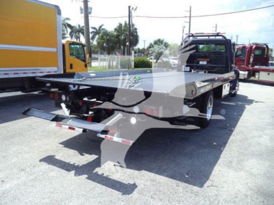 Flatbed tow truck with a hydraulic rollback bed, rear view showing chrome ramps and warning lights, Freightliner M2 106 Plus chassis in a dealership lot.
