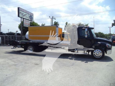 Freightliner M2 106 Plus rollback truck with black cab and yellow tank, side view, VIN tag not visible.