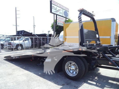 Freightliner M2 106 Plus rollback truck with low-profile flatbed and wheel, side view showing yellow cab, rollover equipment, and hydraulic system