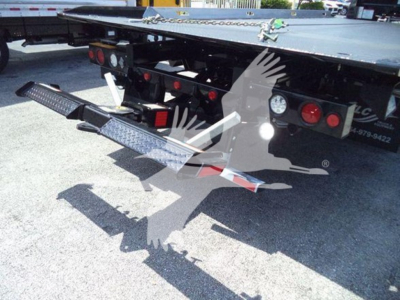 Truck trailer with a loading ramp and rear bumper of a Freightliner M2 106 Plus showing metal steps and taillights.