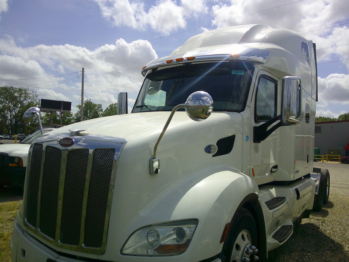 Peterbilt 579 conventional sleeper truck in light color, front grille, side mirrors, and aerodynamic cab with chrome accents.