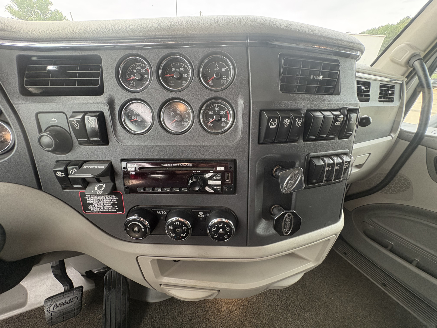 Peterbilt 579 cab interior dashboard cluster with multiple gauges, switches, and climate controls visible.