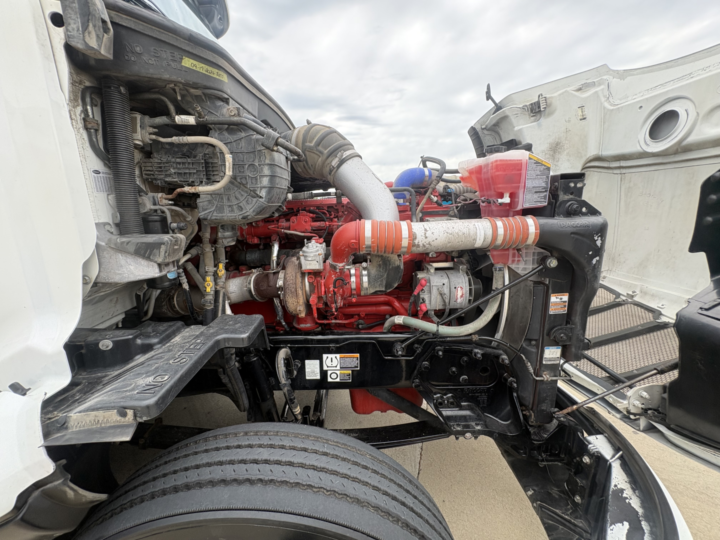 Peterbilt 579 engine bay showing red engine and surrounding hoses and components.