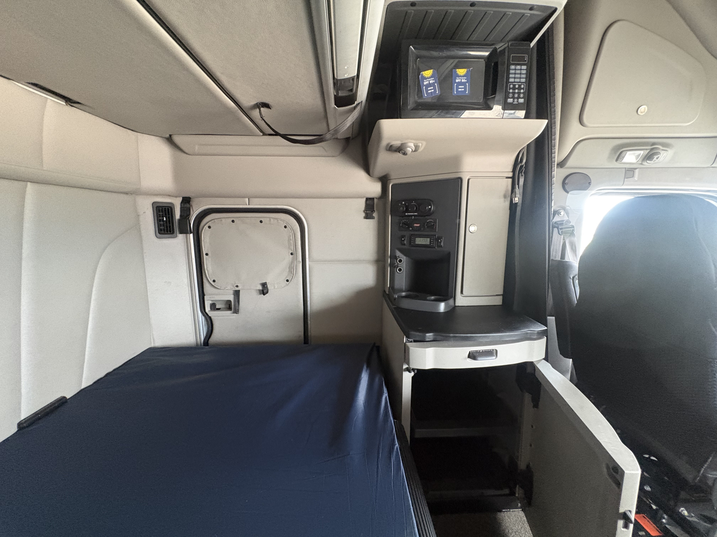 Peterbilt 579 sleeper cab interior showing bunk bed with side cabinet and control panel area.