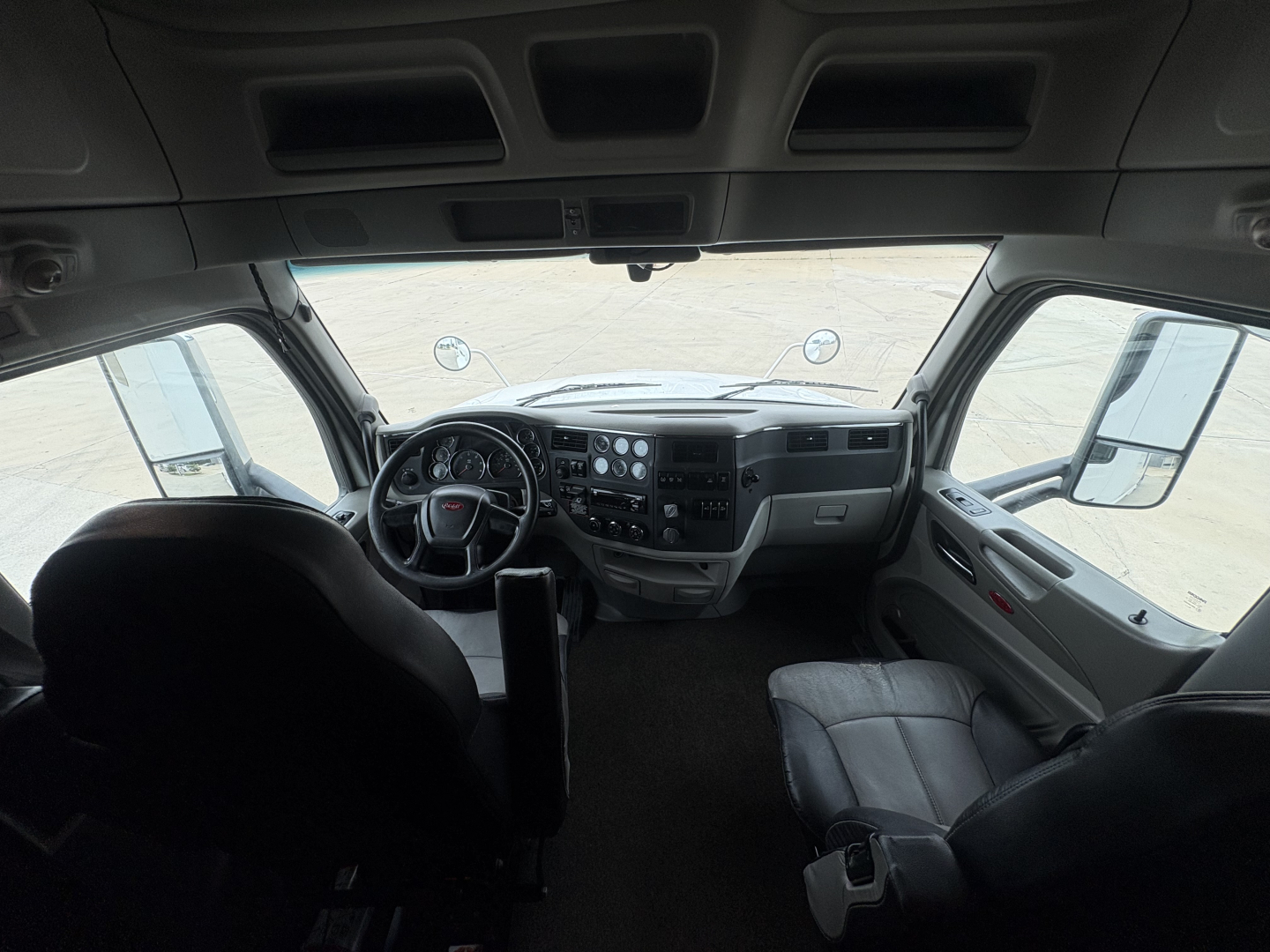 Interior driver cabin of a Peterbilt 579 truck showing dashboard, steering wheel, and front seats.