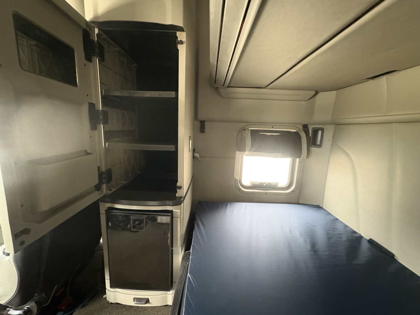 Peterbilt 579 sleeper cab interior showing bunk bed area and open cabinet with mini-fridge