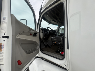 Peterbilt 579 truck cab interior and doorway view from open driver-side door, white exterior, dashboard and steering wheel visible.