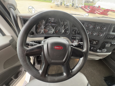 Peterbilt 579 interior dashboard and steering wheel view with multiple gauges and controls visible.