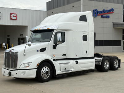 Peterbilt 579 sleeper cab tractor in white, side view with tractors, year 2020, showing cab and dual rear axles, front grille and wheels.