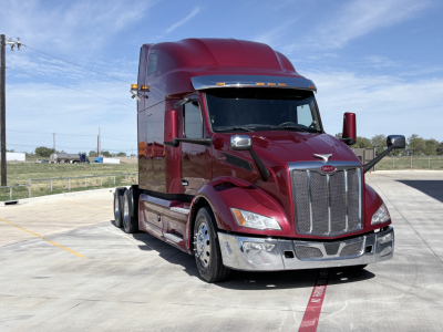 Peterbilt 579 conventional sleeper truck in burgundy showing chrome grille, front bumper, headlights, and side mirrors.
