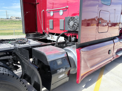 Peterbilt truck fuel/air tanks and cab area showing TriPac APU unit label and side of sleeper cab with red paint