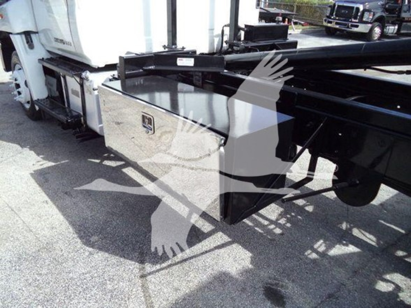 Pickup truck with hooklift chassis showing side-mounted toolbox and hydraulic components.