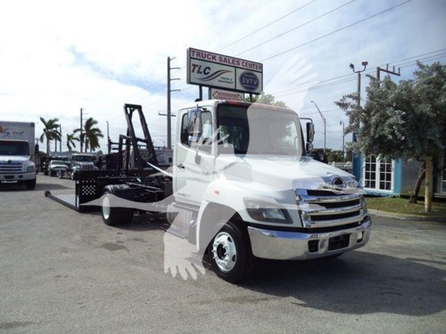 2017 Hino 258Lp hooklift truck in a dealership lot with crane/hooklift equipment attached, front view.