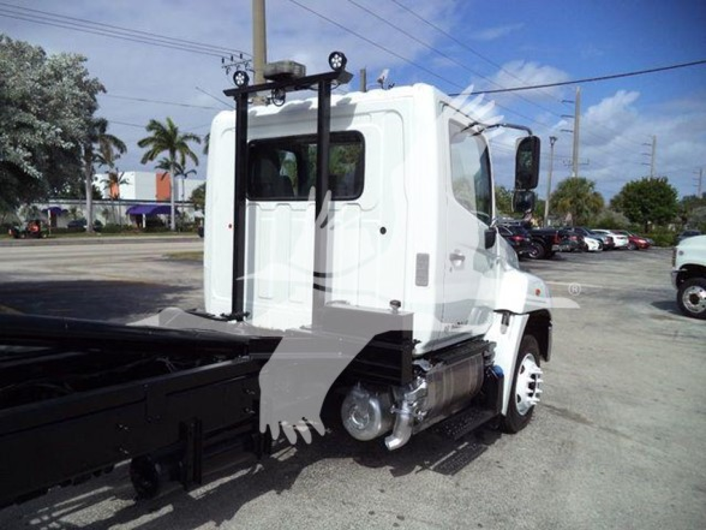 2017 Hino 258LP hooklift truck side view showing cab and chassis with hooklift hoist system, white cab, black flatbed, and equipment mounts.