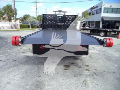 Flatbed hooklift truck rear view showing platform and red taillights with mounted hydraulic mechanism.