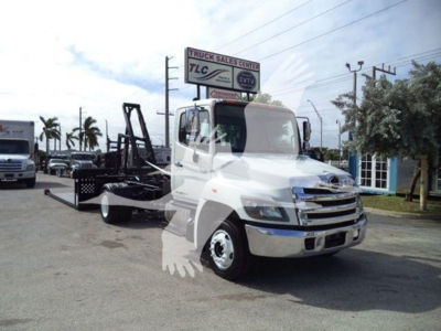 2017 Hino 258Lp hooklift truck in a dealership lot with crane/hooklift equipment attached, front view.