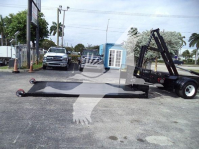 Hino 258LP hooklift truck with long flatbed and hoist arms in a parking lot.