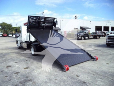Rear view of a 2017 Hino 258LP hooklift truck with a tilted steel loading platform and red rollers on the ground.