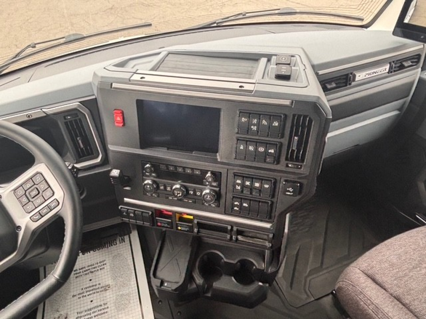 Truck cab dashboard with multiple control panels, infotainment screen, and steering wheel visible.