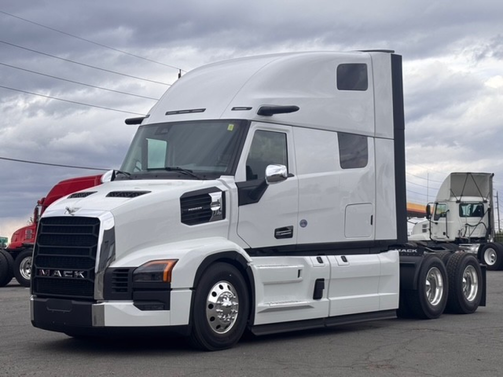 Mack PR64T76H tractor-trailer showing cab with high roof and black front grille, white exterior, dual rear axles, and chrome mirrors.