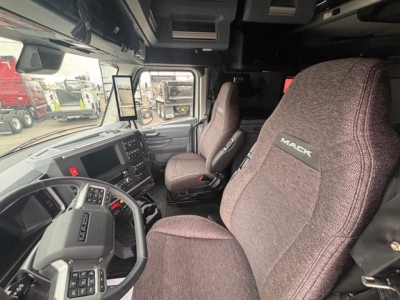 Cab interior of a new 2026 Mack PR64T76H tractor-trailer showing steering wheel, dashboard, and brown fabric seats with Mack branding.