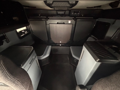 Cab interior of a 2026 Mack PR64T76H showing sleeper area with side cabinets and overhead storage.