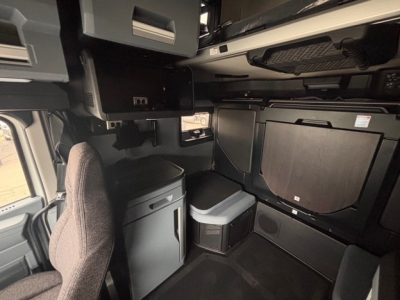 Truck cab interior showing storage compartments, seating, and overhead bunk area.
