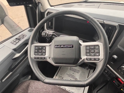 Mack PR64T76H truck interior showing steering wheel with controls on both sides and dashboard display.