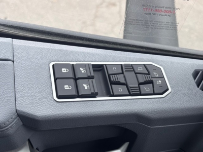 Cab interior window control panel with multiple switches in a Mack PR64T76H truck cabin view