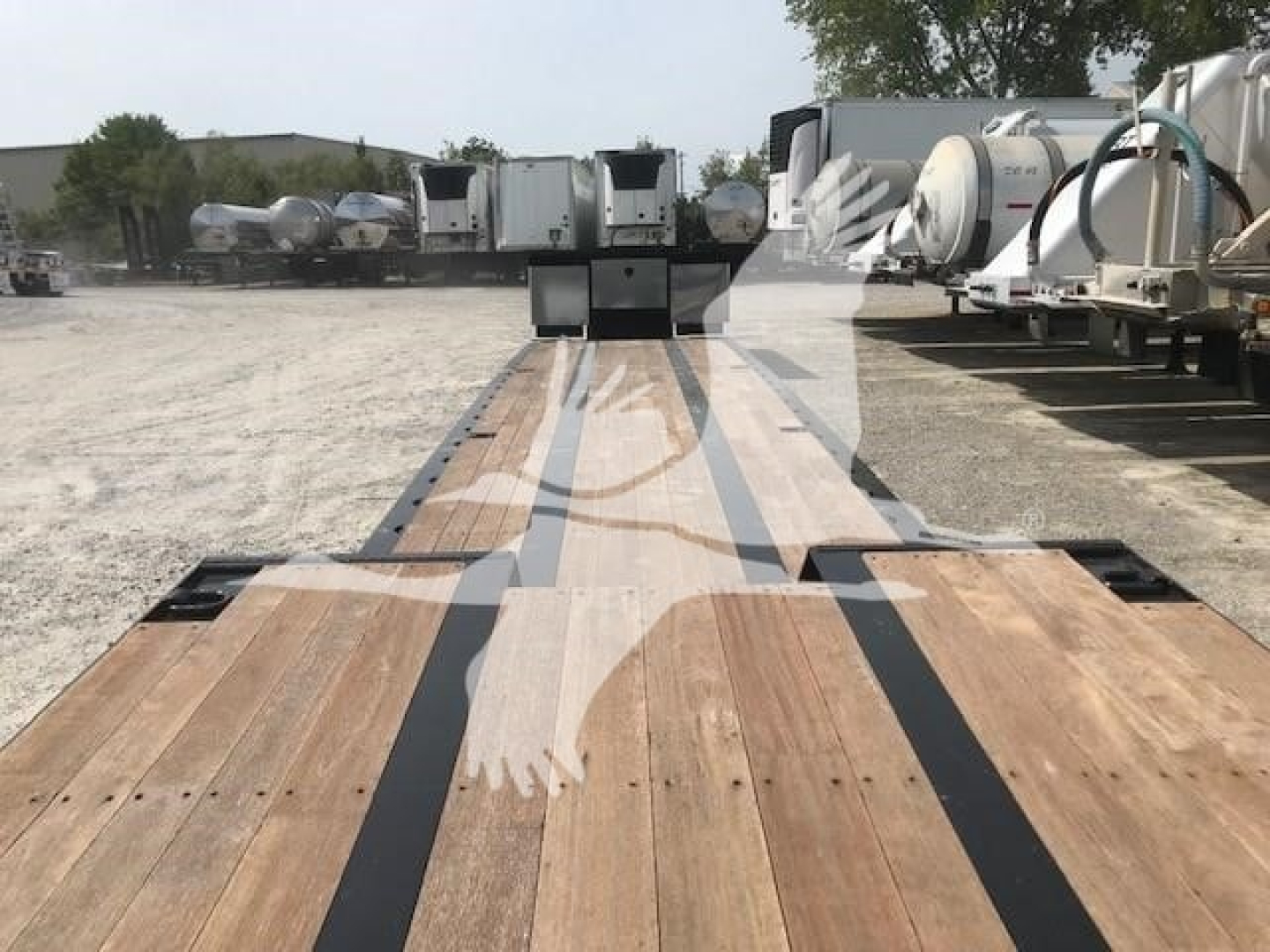 Trailer deck view showing wooden planks with black stripe markings on a XL Specialized XL80MFG trailer, storage yard in background.