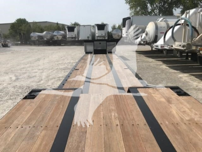 Trailer deck view showing wooden planks with black stripe markings on a XL Specialized XL80MFG trailer, storage yard in background.