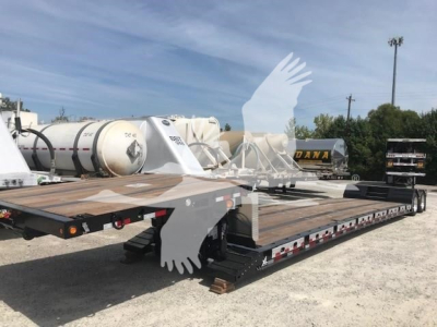 Lowboy trailer showing flatbed deck and dual axles with wood planks and safety reflectors.