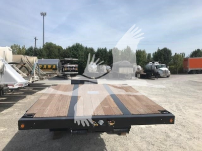 Lowboy trailer deck viewed from rear showing wooden planks and mass-capable frame with taillights.