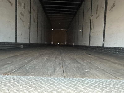 Trailer interior showing empty cargo area with wood floor and sidewalls, Hyundai air ride dry van trailer interior view from rear access opening.