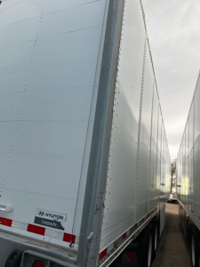 Hyundai air ride dry van trailer side view showing rear portion with composite label and roll-up door area.