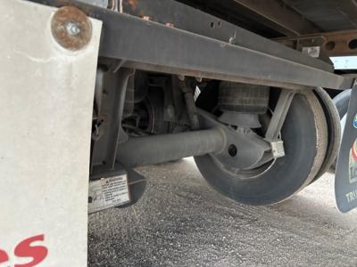 Trailer undercarriage showing wheel, suspension, and frame of an opening-rim warm air ride dry van with a metal bracket and cylindrical axle components.