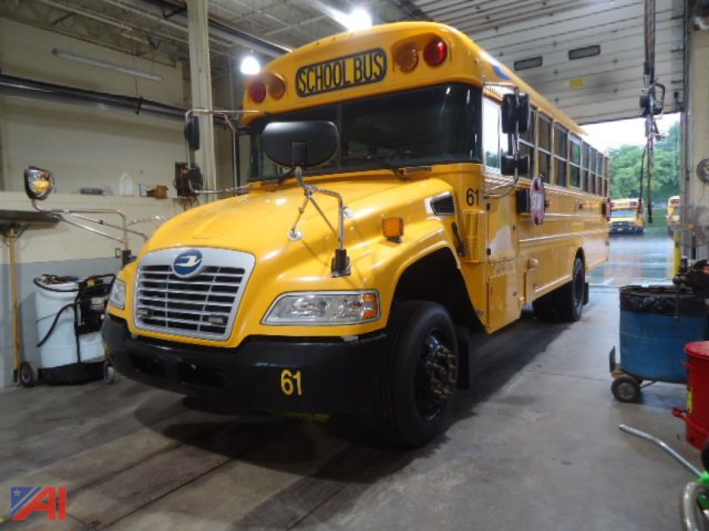 School bus in a workshop with yellow exterior and 'SCHOOL BUS' sign on front, number 61 on bumper, wheelchair accessibility bus.