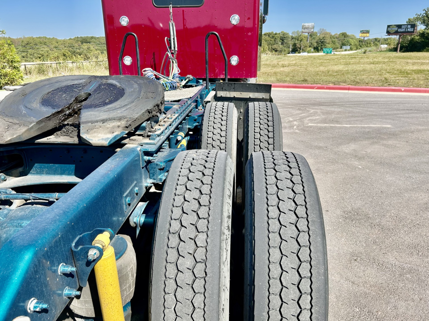 Kenworth W900L chassis and dual rear axles showing tires and part of frame with spare wheel visible.