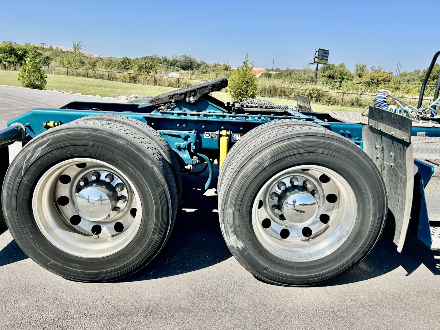 Kenworth W900L chassis showing dual rear wheels and suspension, no cab visible, blue frame with chrome hubcaps and tires.