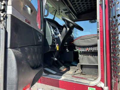 Kenworth W900L truck cab interior view showing driver seat and dashboard with red exterior edge; step area and open door.
