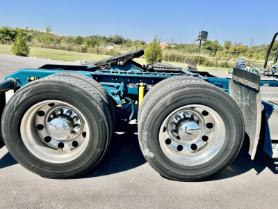 Kenworth W900L chassis showing dual rear wheels and suspension, no cab visible, blue frame with chrome hubcaps and tires.