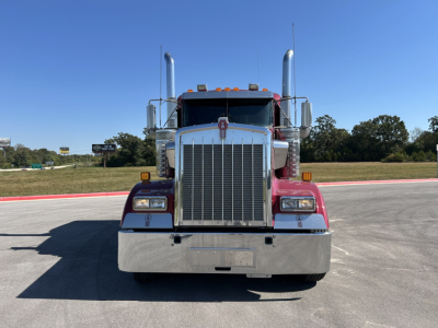 Kenworth W900L truck front view showing large chrome grille, dual tall exhaust stacks, headlights, and bumper.