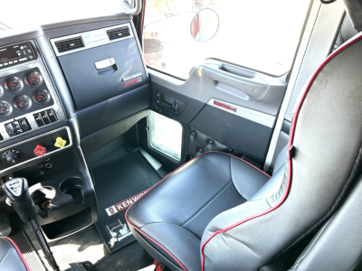 Kenworth W900L interior cab dashboard and driver seat with steering column, gauges, and Kenworth floor mat visible.