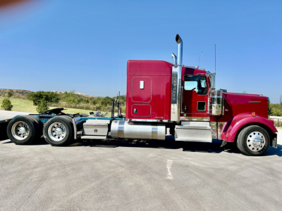 Kenworth W900L conventional sleeper tractor in maroon with chrome exhaust stacks and silver fuel tanks, side view.