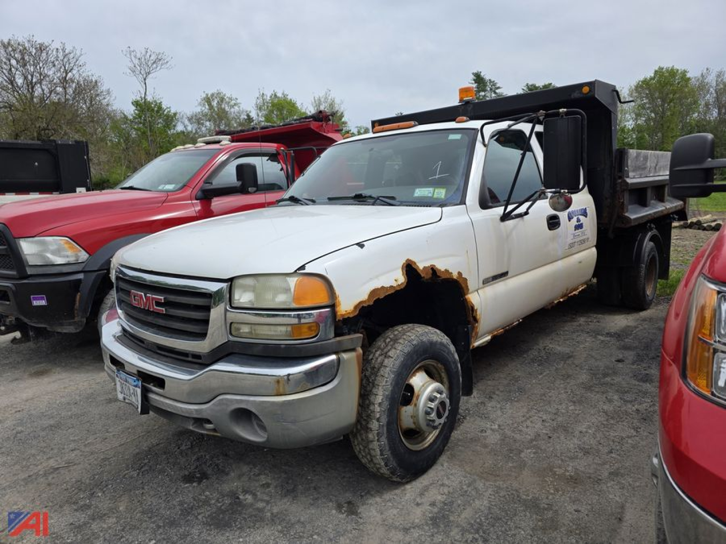 GMC Sierra 3500 dump truck side view showing damaged front fender and open dump bed, white cab with rust on passenger side and badge visible.
