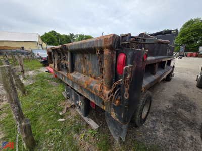 Dump truck bed on a 2004 GMC Sierra 3500 with visible rust and hydraulic tailgate in a lot.