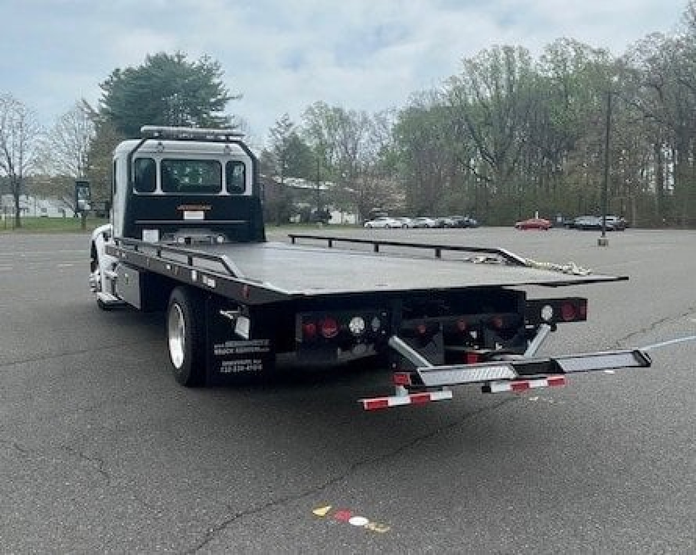 Kenworth T280 flatbed tow truck rear view showing platform bed and rear underride guard with lights.