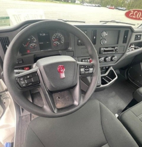 Kenworth T280 interior view showing steering wheel with red emblem, dashboard gauges, and center console controls.